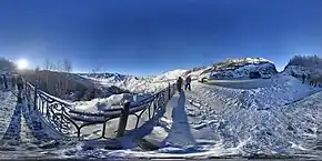 Photographie 360° du point d'observation du Tchike-Taman, en hiver, avec un enneigement important dans le paysage. Le point donne sur une vallée enneigée, et un parking se trouve sur le côté de l'image.