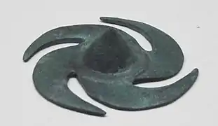 Ornement de bouclier en forme de moulinet.