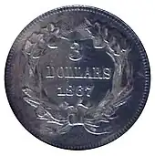 Une pièce de monnaie argentée comprenant une couronne de feuilles à l'intérieur de laquelle se trouvent les inscriptions 3 DOLLARS ET 1867.