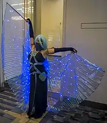 Personne déguisée dans une robe de couleur nuit et avec une perruque bleue.