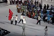 Han Yueshang portant le drapeau de Hong Kong devant deux autres sportifs.