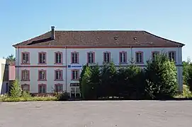 Grand bâtiment blanc à trois étages et toit à quatre pans.