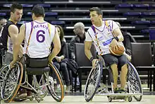 Joueur de basket fauteuil profitant d'un écran d'un coéquipier.