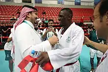 Deux hommes sourient, l'un congratule l’autre, qui est en uniforme.