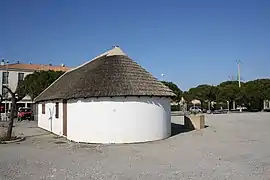 Arrière maçonné en abside sous croupe de roseau.