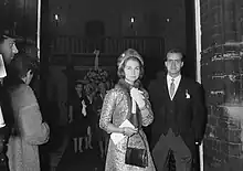 Photographie d'un couple, dont la femme porte un manteau brodé, une toque et une écharpe en fourrure et l'homme un costume trois pièces.