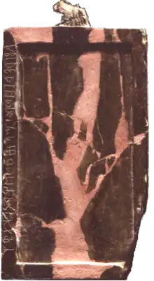 Tablette rectangulaire de petite dimension, de couleur rosée et marron, avec des symboles écrits verticalement sur le côté gauche.