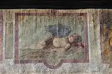 peinture en couleur très abîmée sur un mur, représentant un ange endormi.