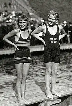 Photographie montrant Aileen Riggin et Nils Skoglund en costumes de bains, debout et côte à côte au bord de l'eau.