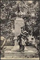 Photographie ancienne montrant une statue dans la quelle le buste d'un homme âgé surplombe des enfants montrant leur reconnaissance.Ancienne statue en hommage à François Mousnier dans le square des Champs Élysées (actuellement jardin Pierre-Mendès-France) à Issoudun en 1916. Fondue pendant la guerre 39-45 afin de fabriquer des munitions, elle a été remplacée depuis par un buste en pierre.