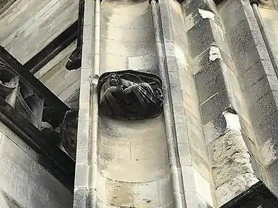 Entre deux niches vides, une sculpture d'un ange soufflant dans un instrument à vent.