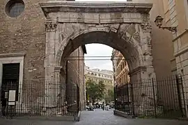 Photographie en couleurs d'un arc de triomphe enjambant une rue entre deux autres bâtiments.