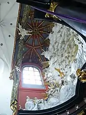 Photographie en contre-plongée d'un décor d'abside baroque et de voûtes à nervures en polychromie.