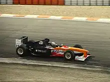 Photographie d'une monoplace de F1, avec l'avant orange et l'arrière, noir.