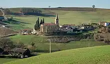 Photo de l'église de l'Assomption : une église à nef unique à proximité de quelques maisons au milieu des champs
