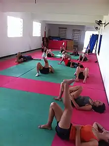 Groupe de personnes allongées au sol et pratiquant l'auto-massage dans une salle de sport.