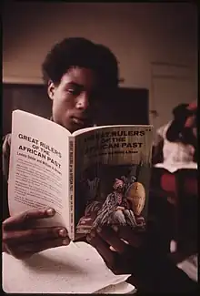 BLACK STUDENT IN A BLACK STUDIES CLASS IN A WEST SIDE CHICAGO CLASSROOM READING A BOOK ABOUT GREAT RULERS IN AFRICA'S... -