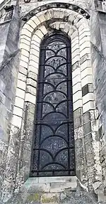 Baie de pierre en arc légèrement brisé avec une verrière.