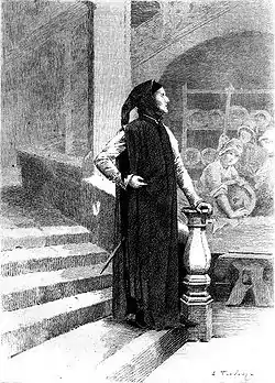 Un homme de profil vêtu de noir au bas d'un escalier regarde vers le lointain, l'air inspiré.