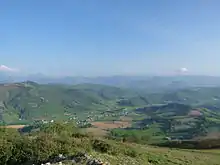 Un paysage de campagne vallonnée et verdoyante, parsemé de quelques hameaux.