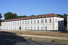 Vue d’un long bâtiment blanc au toit rouge.