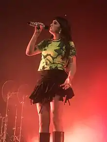 Photographie d'une femme chantant dans un micro sous une lumière rouge.