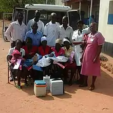 Un groupe de personnes, dont un nouveau-né, pose devant un véhicule sanitaire.