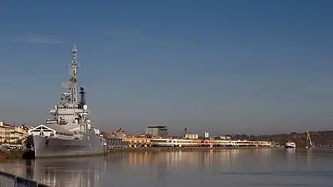 Photo d'un grand navire de guerre gris, de trois-quart face, amarré au calme