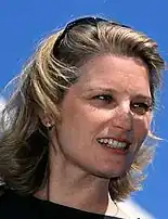 Photographie d'une femme blonde avec des lunettes de soleil dans les cheveux.