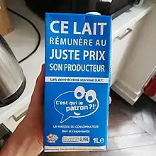 Brique de lait bleue C'est qui le Patron ?! tenue dans une main