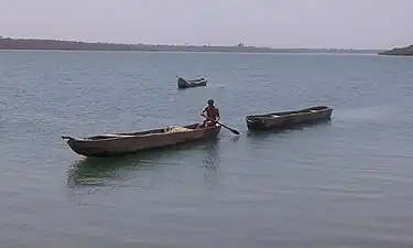 Photographie d'une pirogue en remorquant une autre dans un bras de mer.