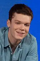 Jeune homme roux portant une chemise et un micro.