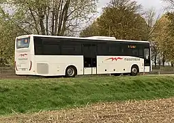 Un autocar de couleur blanche partant en direction de la droite de l'image.
