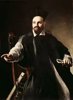 peinture d'un homme barbu en costume et toque noirs, assis dans un fauteuil et pointant du doigt vers sa droite.