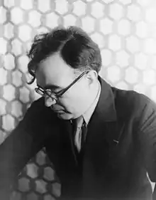 Photographie en noir et blanc d'un homme à lunettes, tourné de profil.