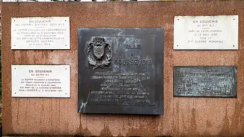 Plaque commémorative devant le centre commercial Charras à Courbevoie (en 2018).
