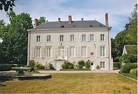 Photographie en couleurs d'un château de deux étages, le toit étant en ardoises ; une pelouse au premier plan.
