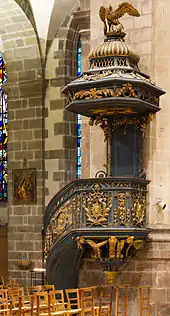 Photographie de la chaire en fer forgé, accolée à un pilier.