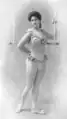 Charmion en tenue d’acrobate (à la fin de son numéro) : elle porte un justaucorps sans manches, orné de fleurs ou de feuillages sur la poitrine, les bretelles et à la ceinture, ainsi que des ballerines légères
