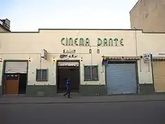 Photographie d'un bâtiment avec l'écriture en néon CINEMA DANTE en vert.