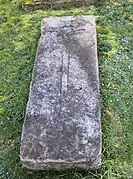Seul vestige de l'ancien cimetière, une croix sculptée sur une pierre tombale à droite de l'église.