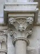 Photographie en couleurs d'un chapiteau aux motifs végétaux remplacés par des figurines humaines.