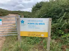 Un panneau blanc marque l'entrée du site du Conservatoire du littoral.