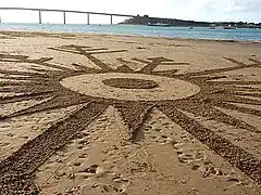Dessin sur le sable de la plage représentant un flocon de neige.