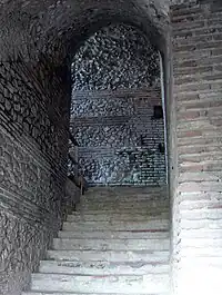 Vue d'un escalier s'engageant sous une voûte antique.