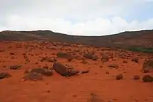 Paysage désertique constitué de blocs et de terres rougeâtre.