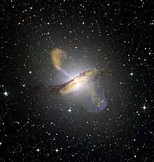 Photographie d'une galaxie, une source lumineuse au centre, formant un anneau et perpendiculairement des lobes moins lumineux.