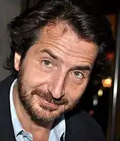 Un homme d'une quarantaine d'années regardant vers l'objectif, le visage légèrement incliné.