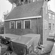 Photographie en noir et blanc d'une remise couronnée d'un pignon et précédée d'un terrain vague.