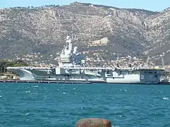 Le Charles de Gaulle à quai à Toulon avec le Mont Faron en arrière-plan.